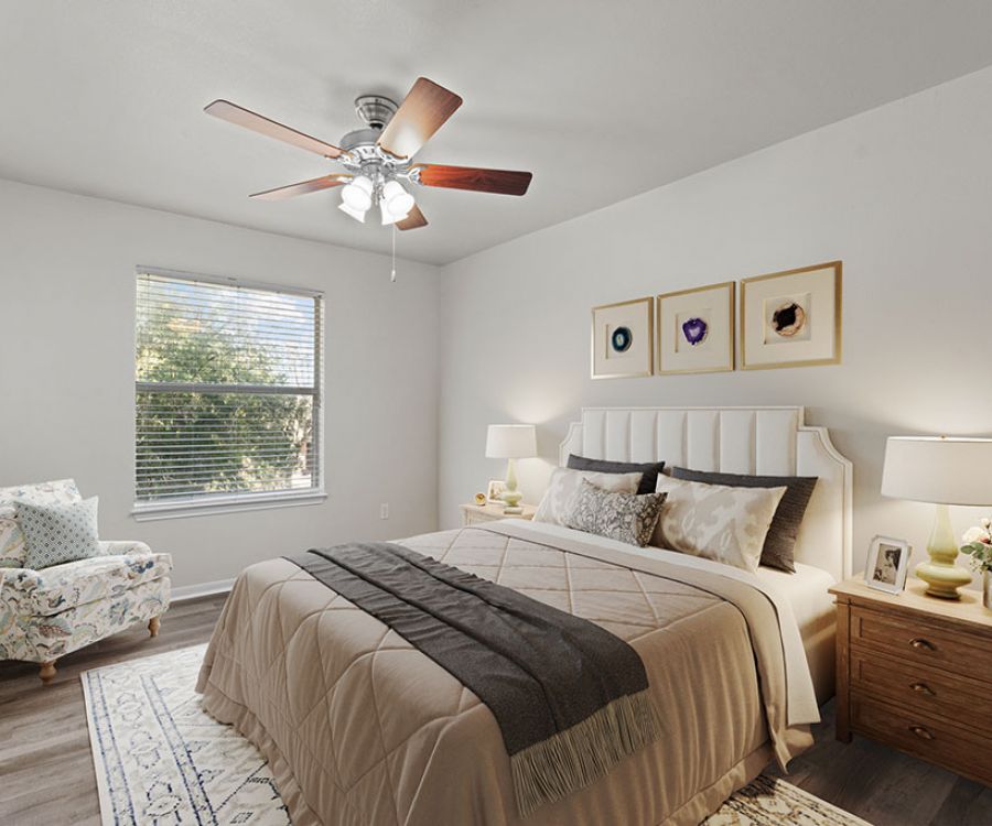 Cozy bedroom at Encino Park with a double bed, patterned armchair, wooden nightstands, and a ceiling fan.